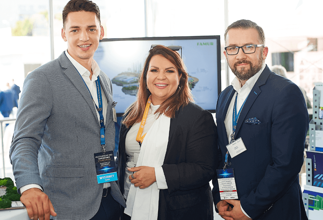 Troje pracowników Projekt Solartechnik na Targach EXPO patrzą uśmiechnięci w stronę aparatu zachęcając do poznania innowacyjnej oferty na farmy solarne i wiatrowe.